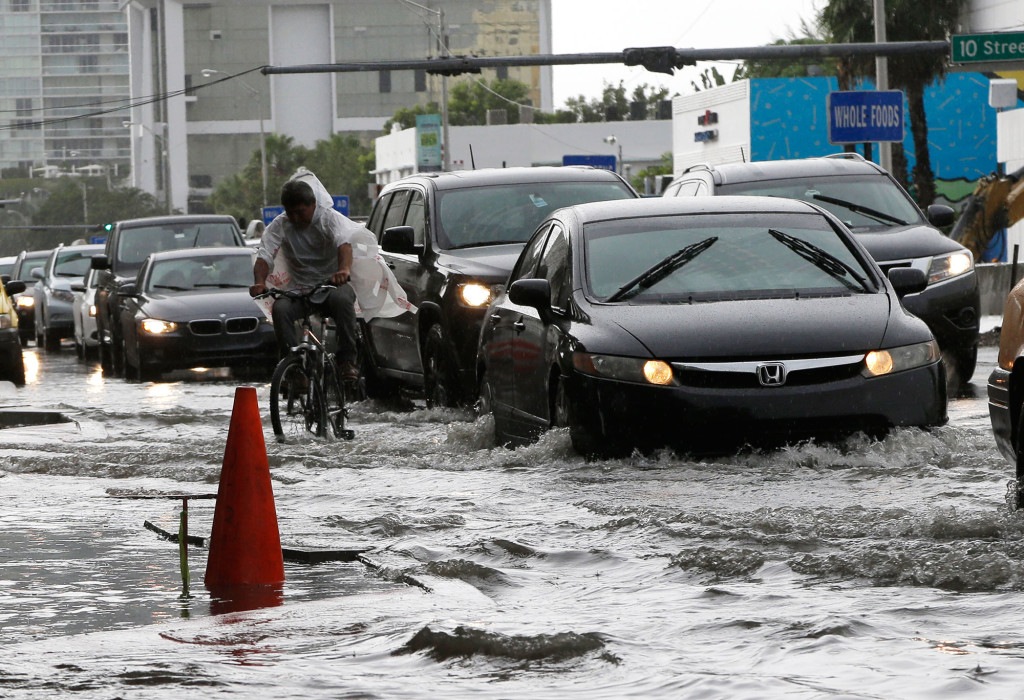 En cyklist försöker ta sig fram på en vattenfylld gata i Miami Beach, Florida. Området drabbas av återkommande översvämningar på grund av kraftiga regn och höga vattenstånd. Foto: AP